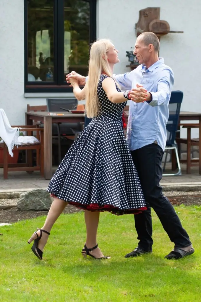 beautiful young couple of newlyweds dancing tango on the lawn in the garden